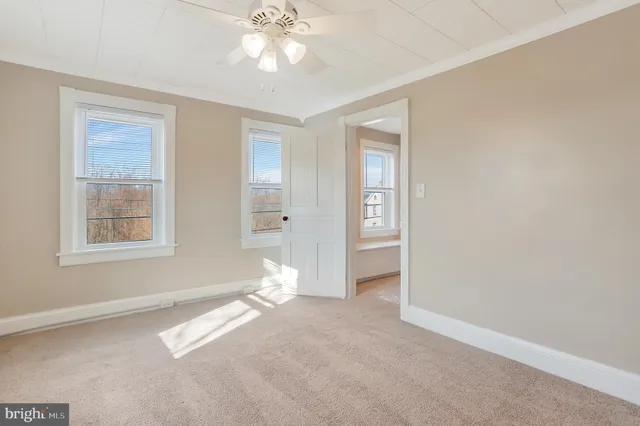 an empty room with windows and fan
