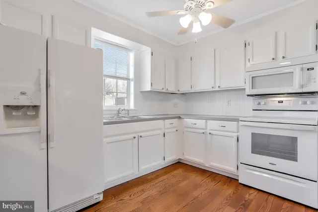 a kitchen with granite countertop white cabinets stainless steel appliances and a window