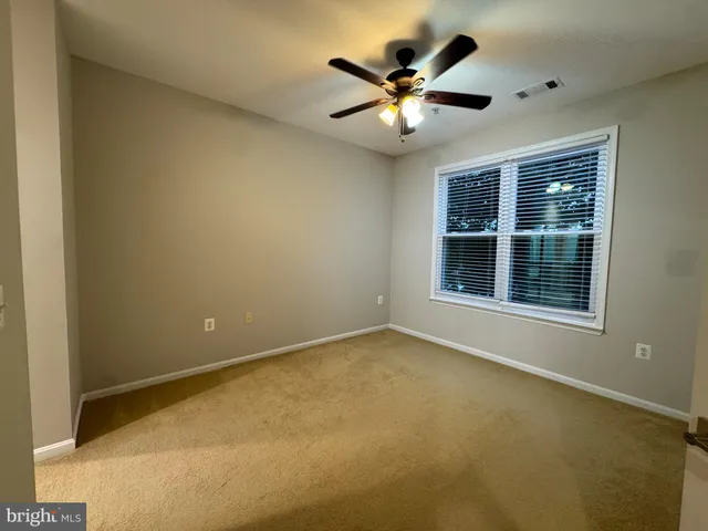 an empty room with chandelier fan and windows