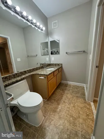 a bathroom with a granite countertop toilet sink and mirror