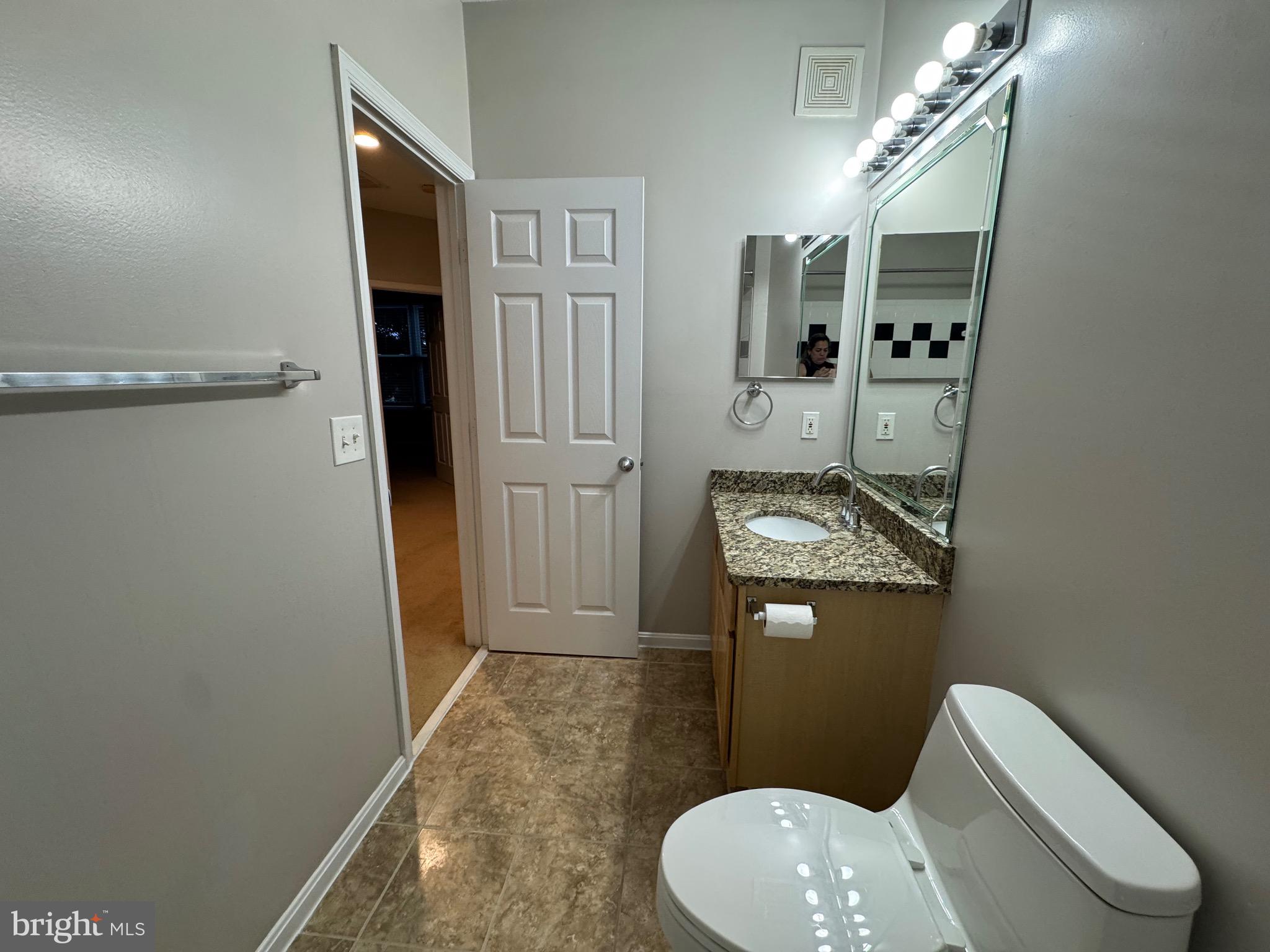 9486 Virginia Center Boulevard, Unit 114 Vienna, VA 22181 - Photo 27 of 41 a bathroom with a granite countertop toilet sink and mirror