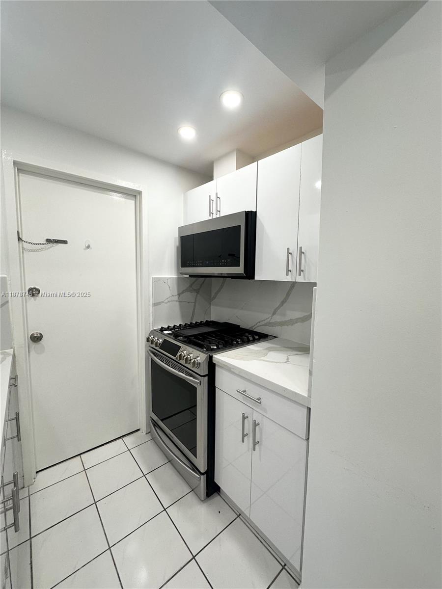 8400 Byron Avenue, Unit 2D Miami Beach, FL 33141 - Photo 10 of 21 a kitchen with stainless steel appliances granite countertop a stove a microwave and a refrigerator