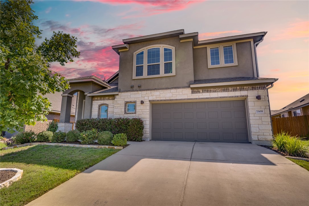 a front view of a house with a garden and garage