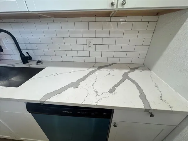 a kitchen with granite countertop a refrigerator and a sink