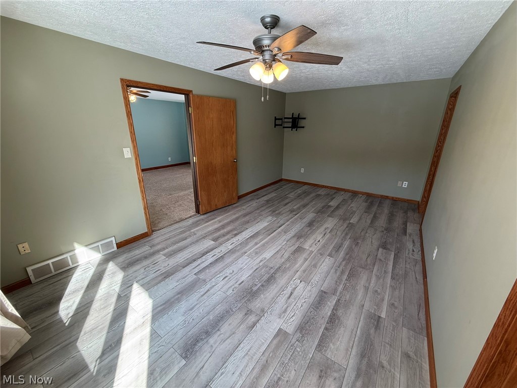 6784 Old Zoarville Road Northeast Dover, OH 44622 - Photo 20 of 50 Unfurnished room with light wood-style flooring, a textured ceiling, and ceiling fan