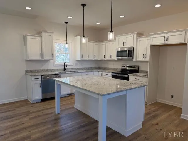 a kitchen with kitchen island stainless steel appliances a sink a stove a refrigerator and a center island