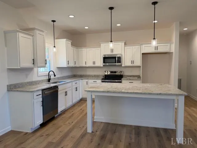 a kitchen with kitchen island granite countertop a sink a counter space appliances and cabinets