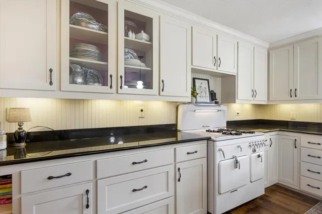 a kitchen with granite countertop white cabinets and stainless steel appliances