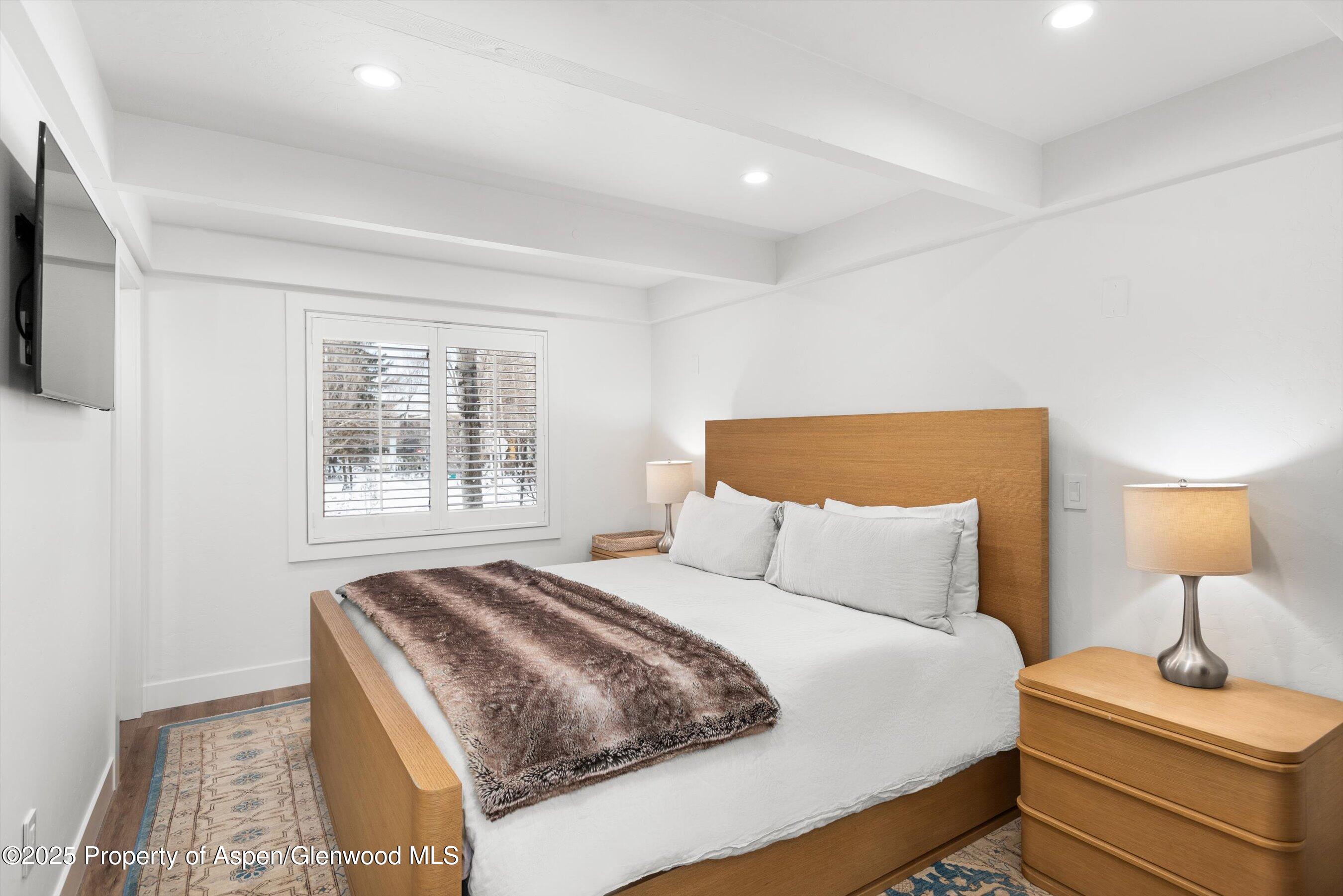 901 East Hyman Avenue, Unit 1 Aspen, CO 81611 - Photo 3 of 12 a bedroom with a bed and a lamp on dresser