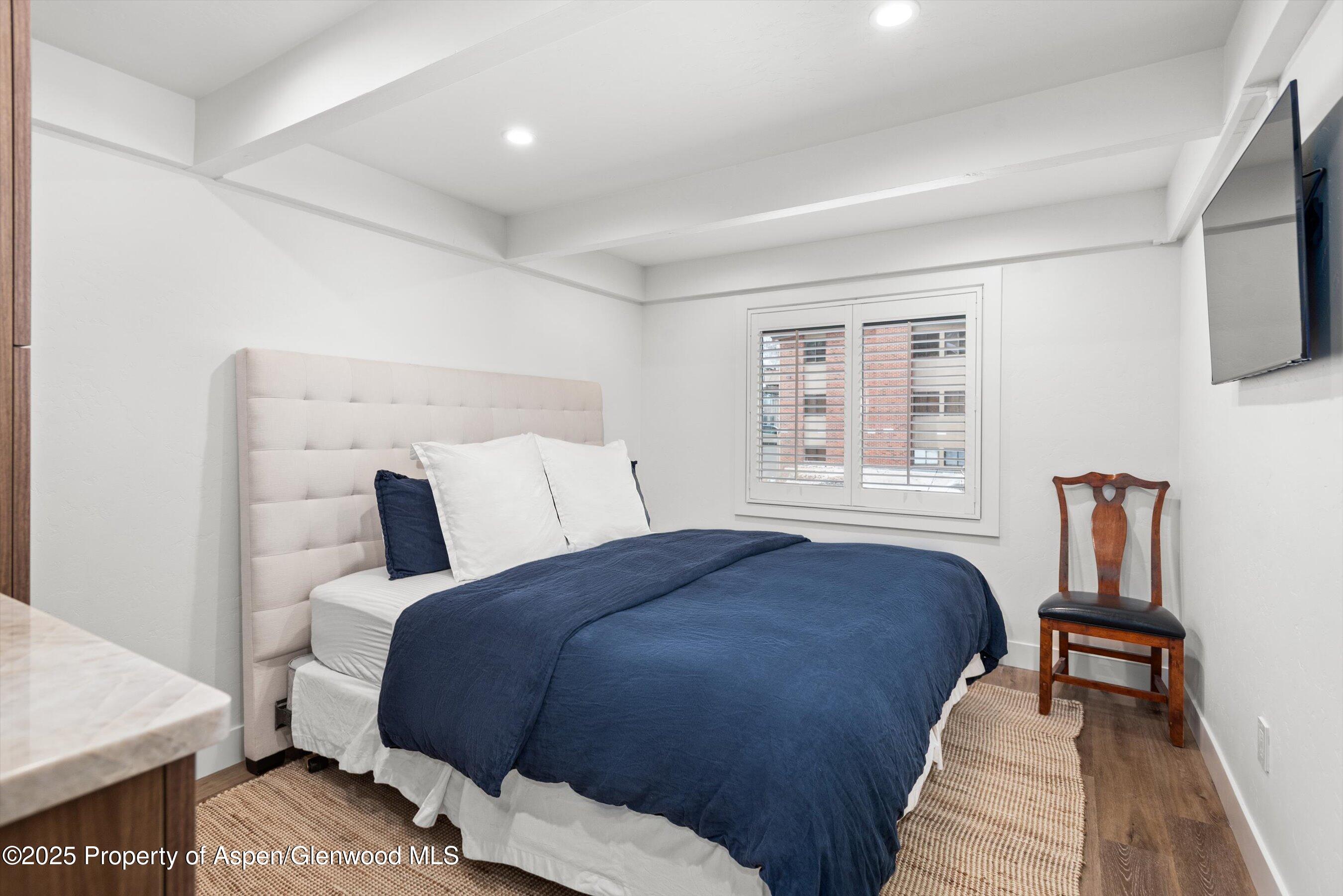 901 East Hyman Avenue, Unit 1 Aspen, CO 81611 - Photo 6 of 12 a bedroom with a bed and wooden floor