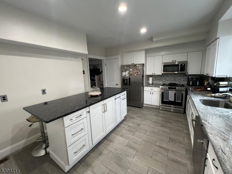865 Westfield Avenue Elizabeth, NJ 07208 - Photo 25 of 26 a kitchen with stainless steel appliances a stove top oven a sink a refrigerator white cabinets and wooden floor