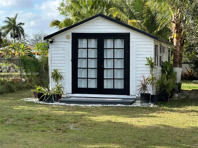 a view of a house with a yard potted plants and large tree