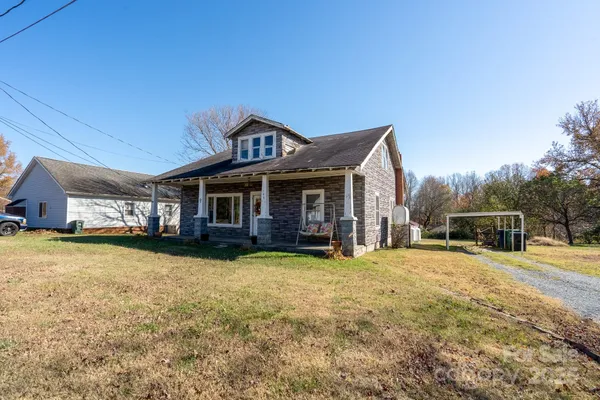 a view of a house with a big yard and large trees