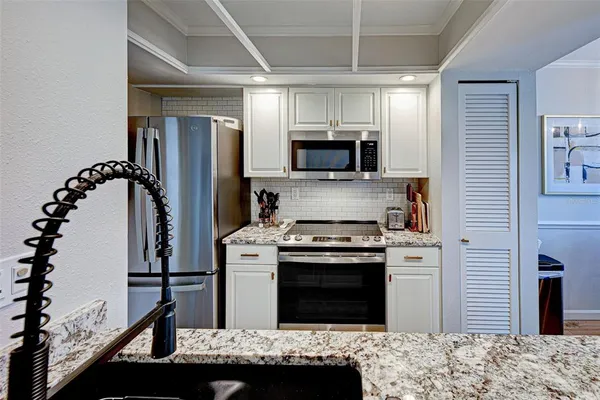 a kitchen with kitchen island stainless steel appliances sink stove microwave and refrigerator