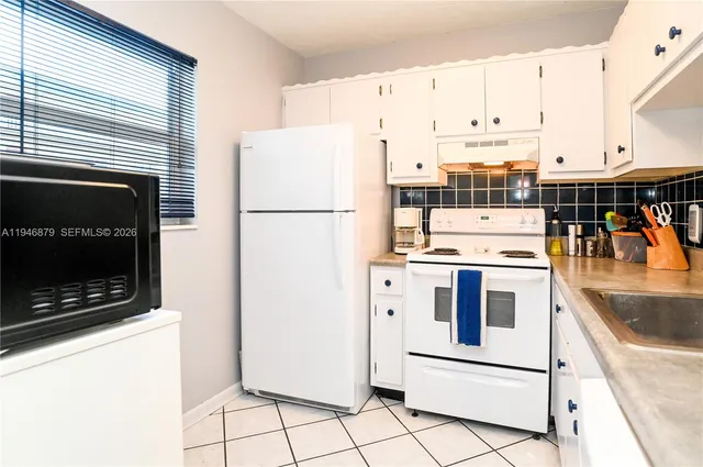 a kitchen with a stove and a white wooden cabinets
