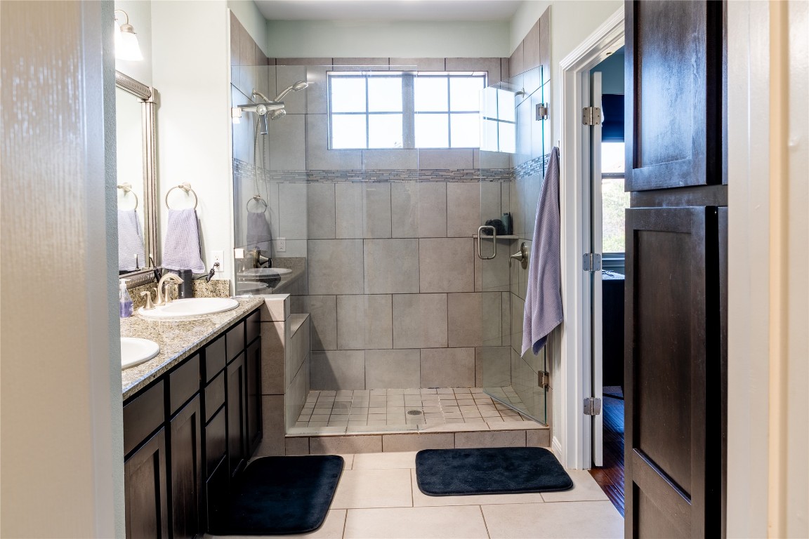 3006 Sea Jay Drive Austin, TX 78745 - Photo 11 of 22 Bathroom with double vanity, a stall shower, and light tile patterned flooring