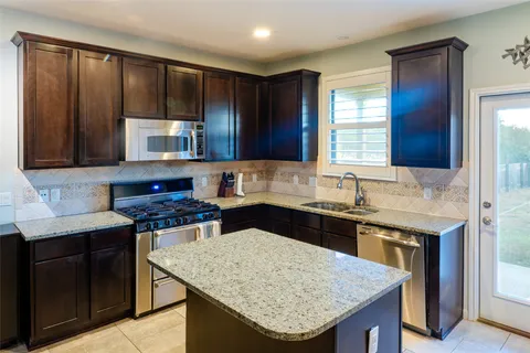 a kitchen with stainless steel appliances granite countertop wooden cabinets a stove and a sink