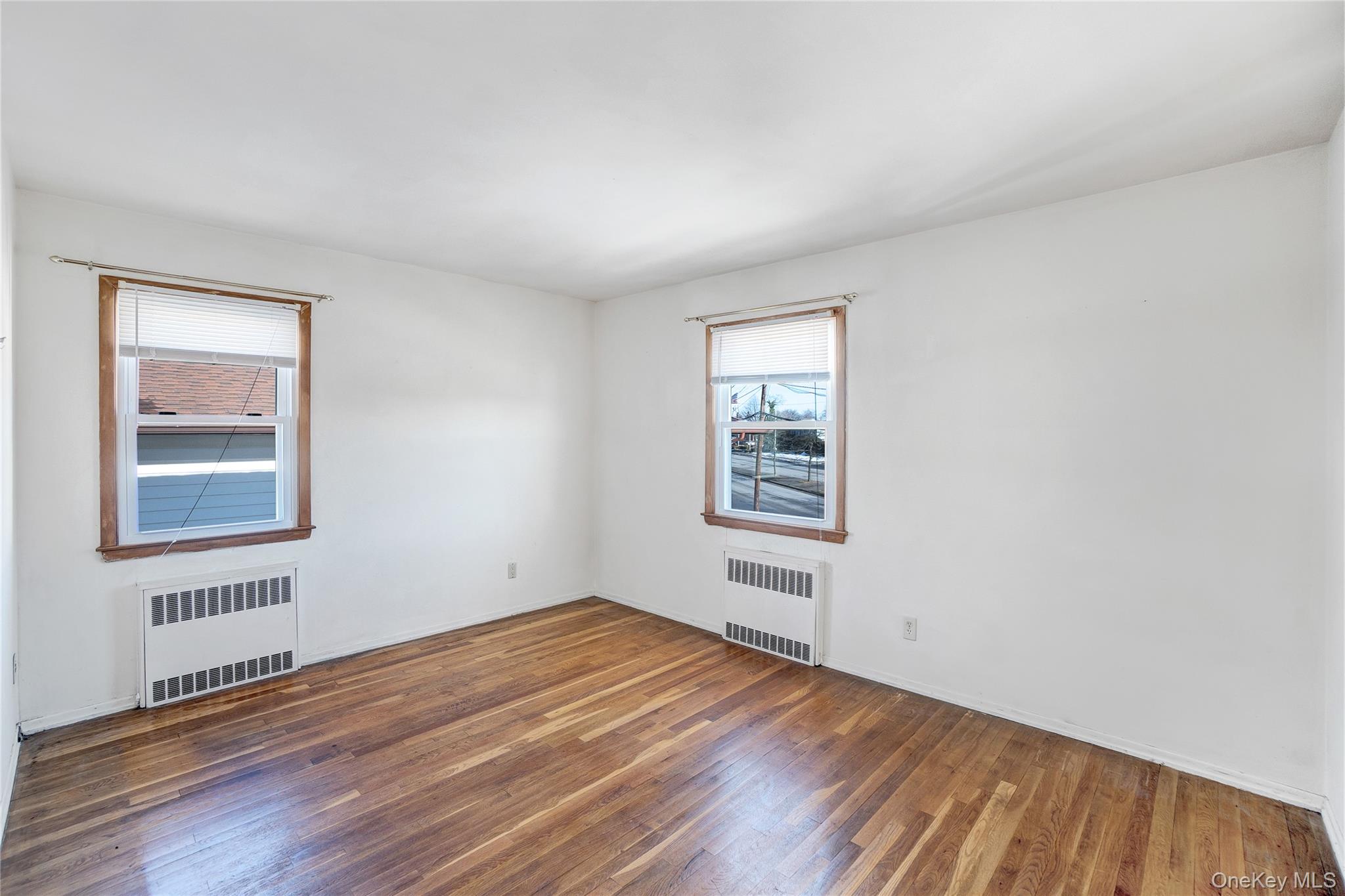 212 Newbridge Road Hicksville, NY 11801 - Photo 12 of 18 Empty room featuring radiator heating unit and wood-type flooring