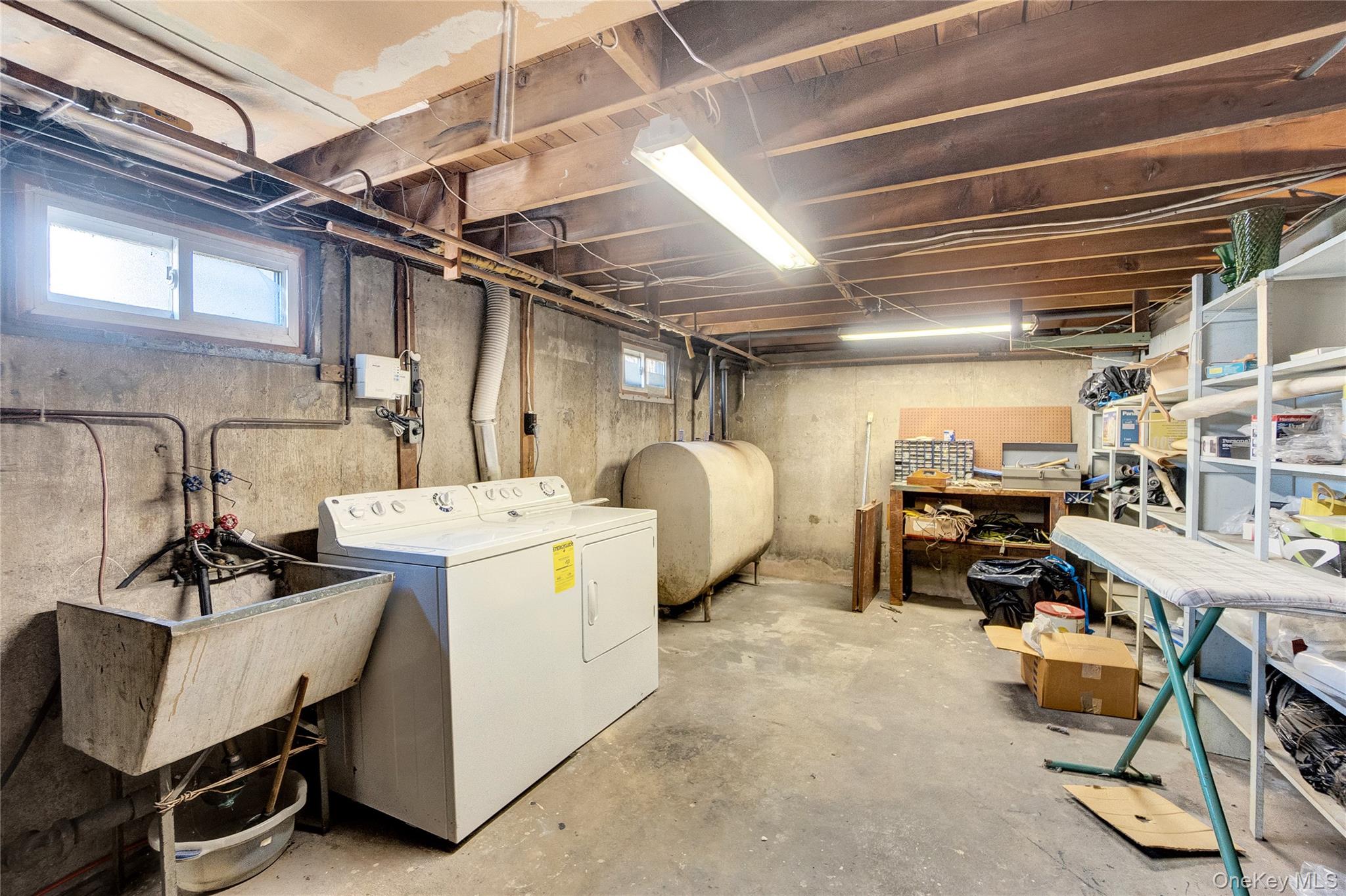 212 Newbridge Road Hicksville, NY 11801 - Photo 14 of 18 Basement featuring heating fuel, washing machine and clothes dryer, and a workshop area