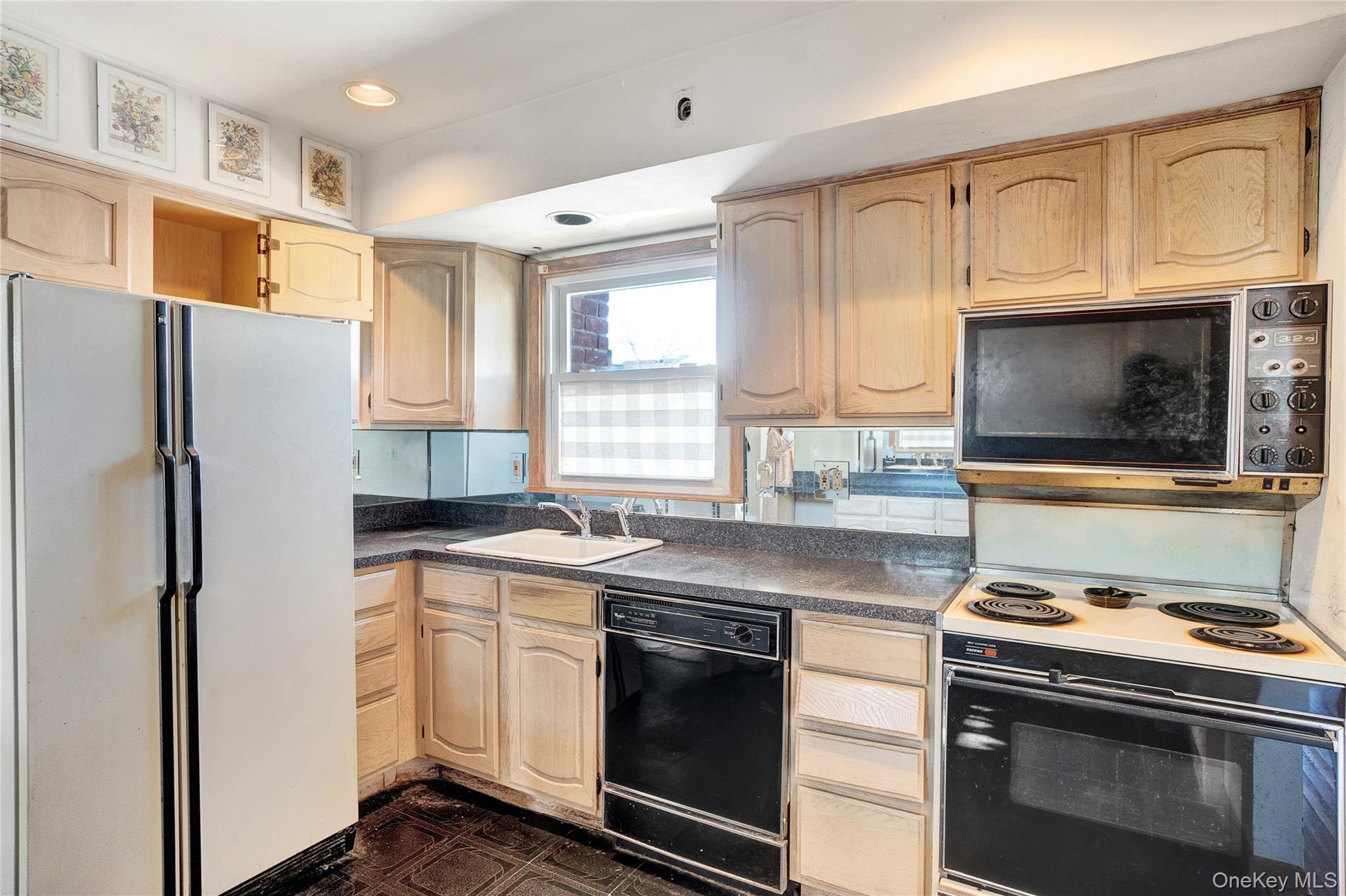 212 Newbridge Road Hicksville, NY 11801 - Photo 4 of 18 Kitchen with black appliances, dark countertops, light brown cabinets, dark flooring, and recessed lighting