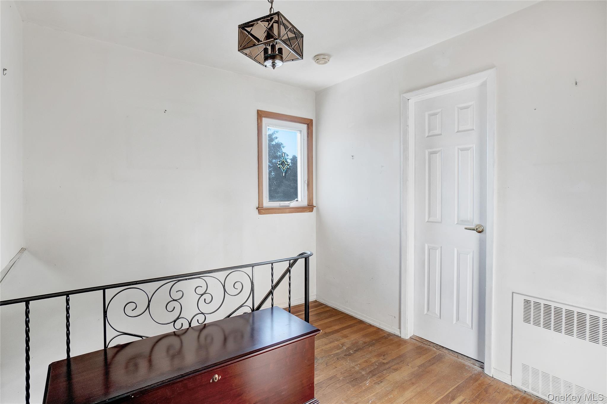 212 Newbridge Road Hicksville, NY 11801 - Photo 8 of 18 Hall featuring radiator, an upstairs landing, and hardwood / wood-style floors