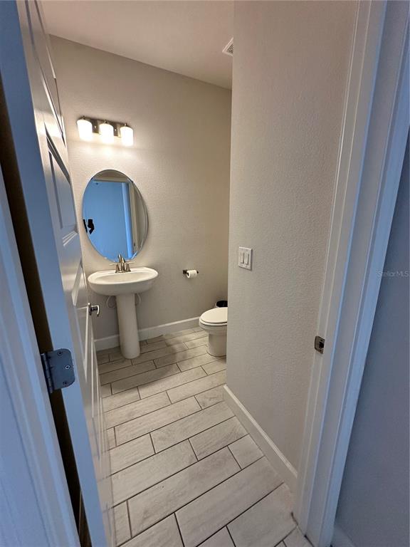 36097 Welsh Glade Road Dade City, FL 33525 - Photo 16 of 35 a bathroom with a toilet sink and mirror
