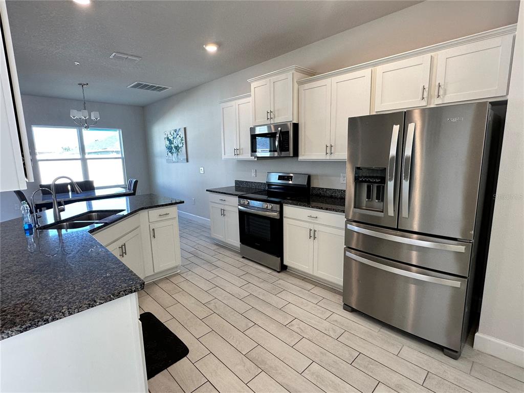 36097 Welsh Glade Road Dade City, FL 33525 - Photo 4 of 35 a kitchen with stainless steel appliances granite countertop a refrigerator a sink a stove a microwave and island