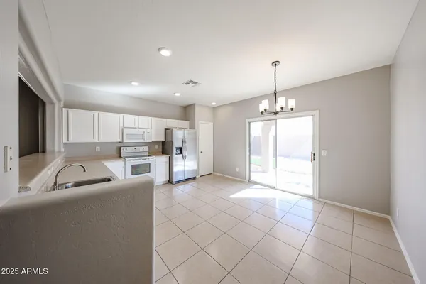 a living room with furniture a chandelier and kitchen view