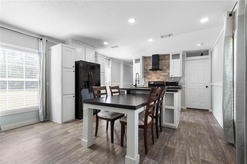 1688 Papaya Street Bunnell, FL 32110 - Photo 12 of 63 a kitchen with stainless steel appliances granite countertop a refrigerator a stove a sink a dining table and chairs