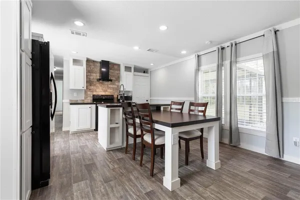 a kitchen with stainless steel appliances a table chairs refrigerator and cabinets