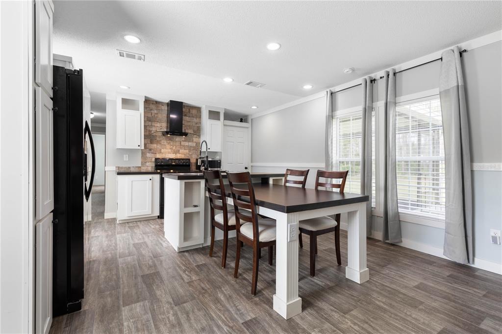 1688 Papaya Street Bunnell, FL 32110 - Photo 2 of 63 a kitchen with stainless steel appliances a table chairs refrigerator and cabinets