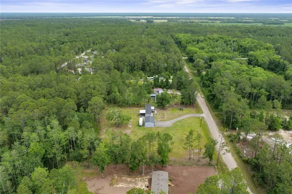 an aerial view of a house with swimming pool and trees