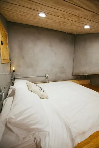 a bedroom with a bed and dresser with wooden floor