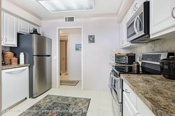 a kitchen with stainless steel appliances granite countertop a refrigerator a stove and a sink