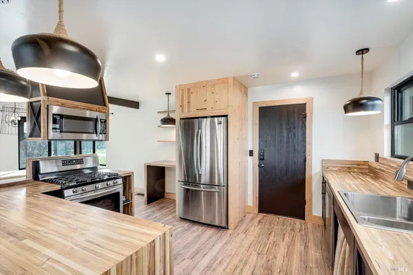 a kitchen with stainless steel appliances granite countertop a refrigerator a stove and a sink with wooden floor