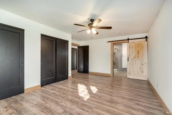 a view of empty room with wooden floor and ceiling fan