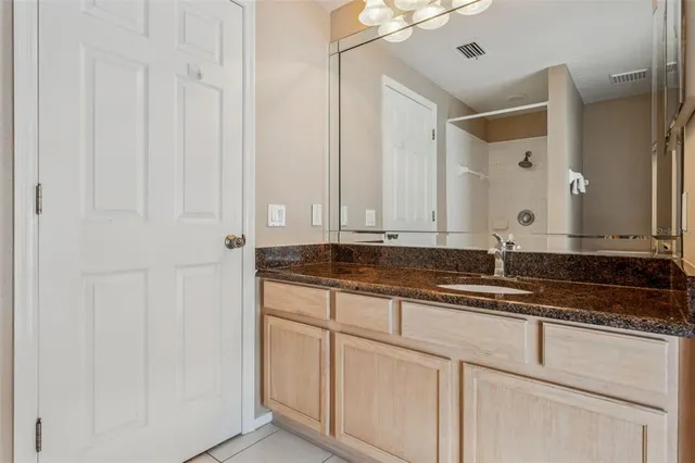 a spacious bedroom with a bed a chandelier and dresser