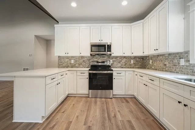 a kitchen with granite countertop wooden floors a stove and a microwave