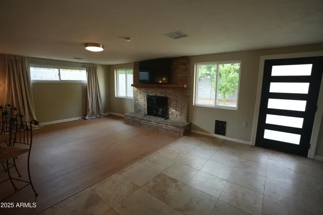 an empty room with windows fireplace and wooden floor
