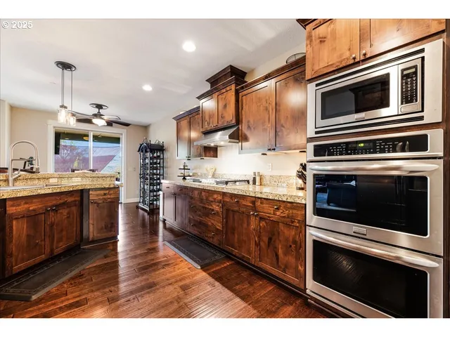 a kitchen with stainless steel appliances kitchen island granite countertop a stove microwave and refrigerator
