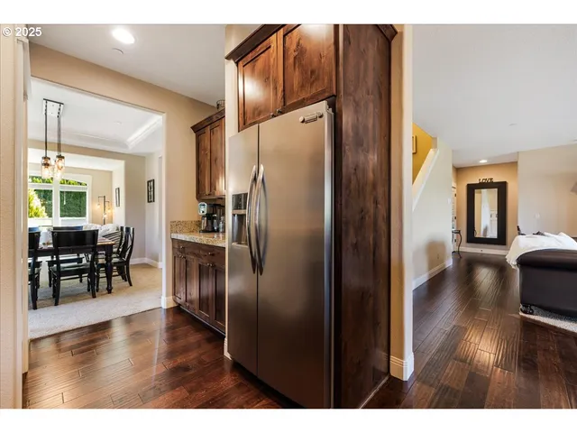 a kitchen with stainless steel appliances granite countertop a refrigerator a stove and a dining table with wooden floor