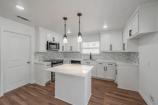 a kitchen with granite countertop a sink a counter space appliances and cabinets
