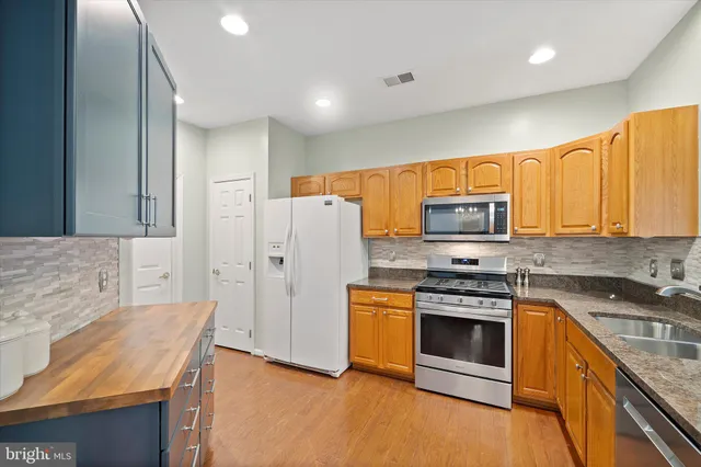 a kitchen with stainless steel appliances granite countertop a stove a sink and a refrigerator