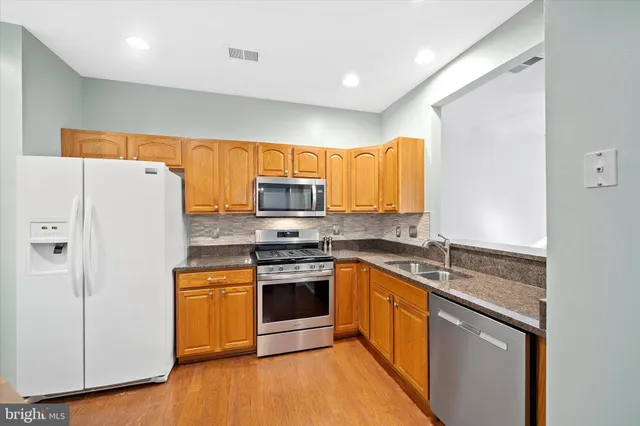 a kitchen with stainless steel appliances granite countertop a stove a sink and a refrigerator