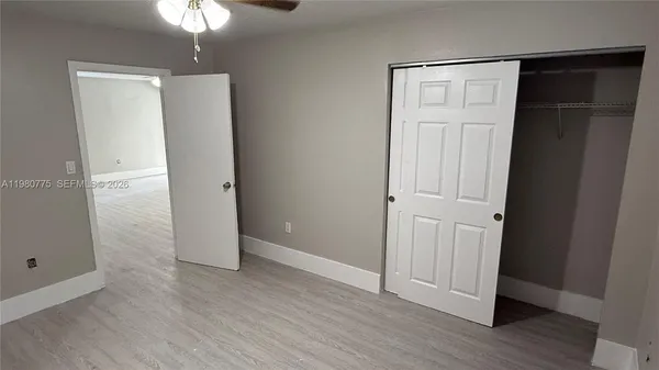 an empty room with wooden floor closet and windows