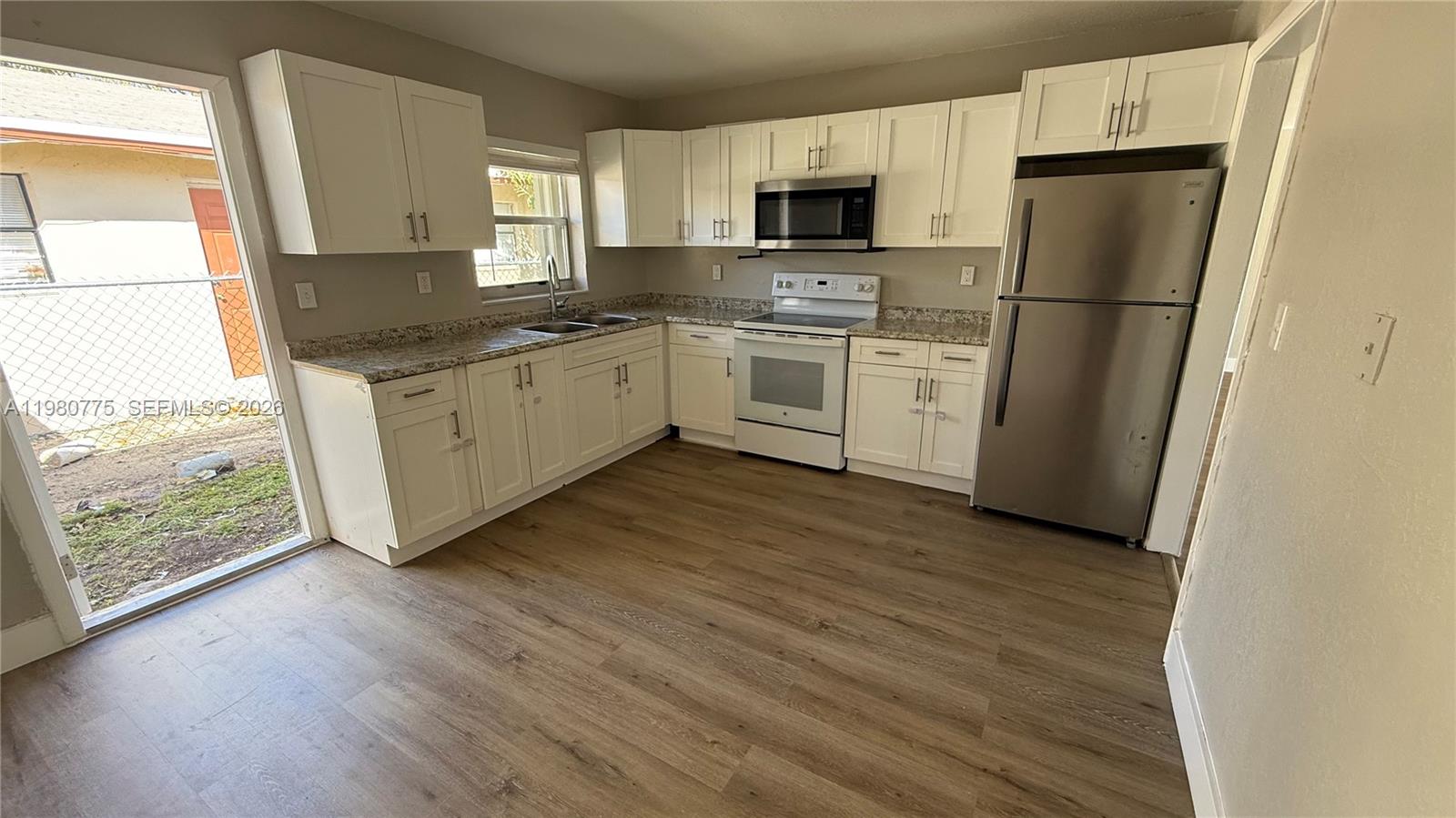 220 Northwest 12th Street Pompano Beach, FL 33060 - Photo 38 of 77 a kitchen with a sink a refrigerator a window and a stove top oven