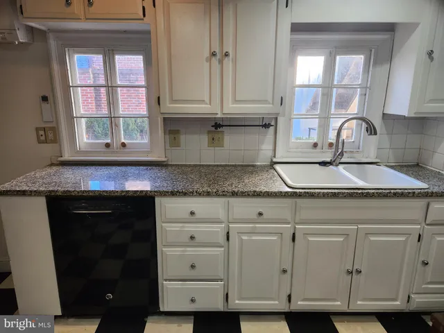 a kitchen with granite countertop white cabinets and sink