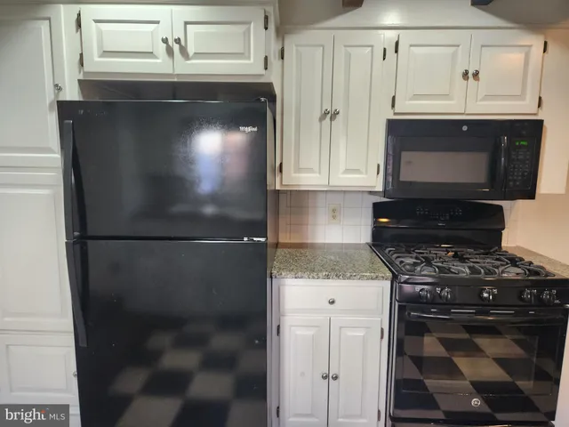 a kitchen with granite countertop a refrigerator a stove a microwave and cabinets
