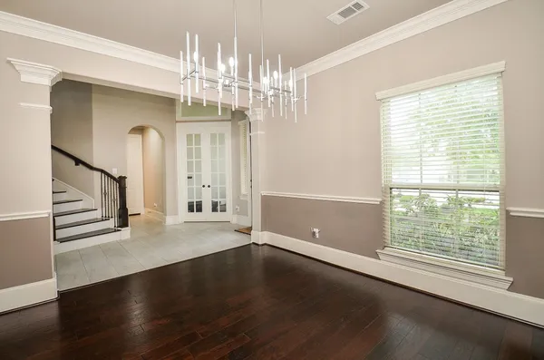a view of a big room with wooden floor chandelier and windows