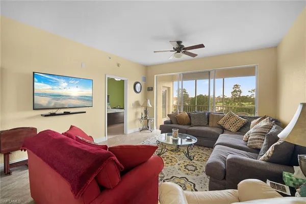 a living room with furniture ceiling fan and a large window